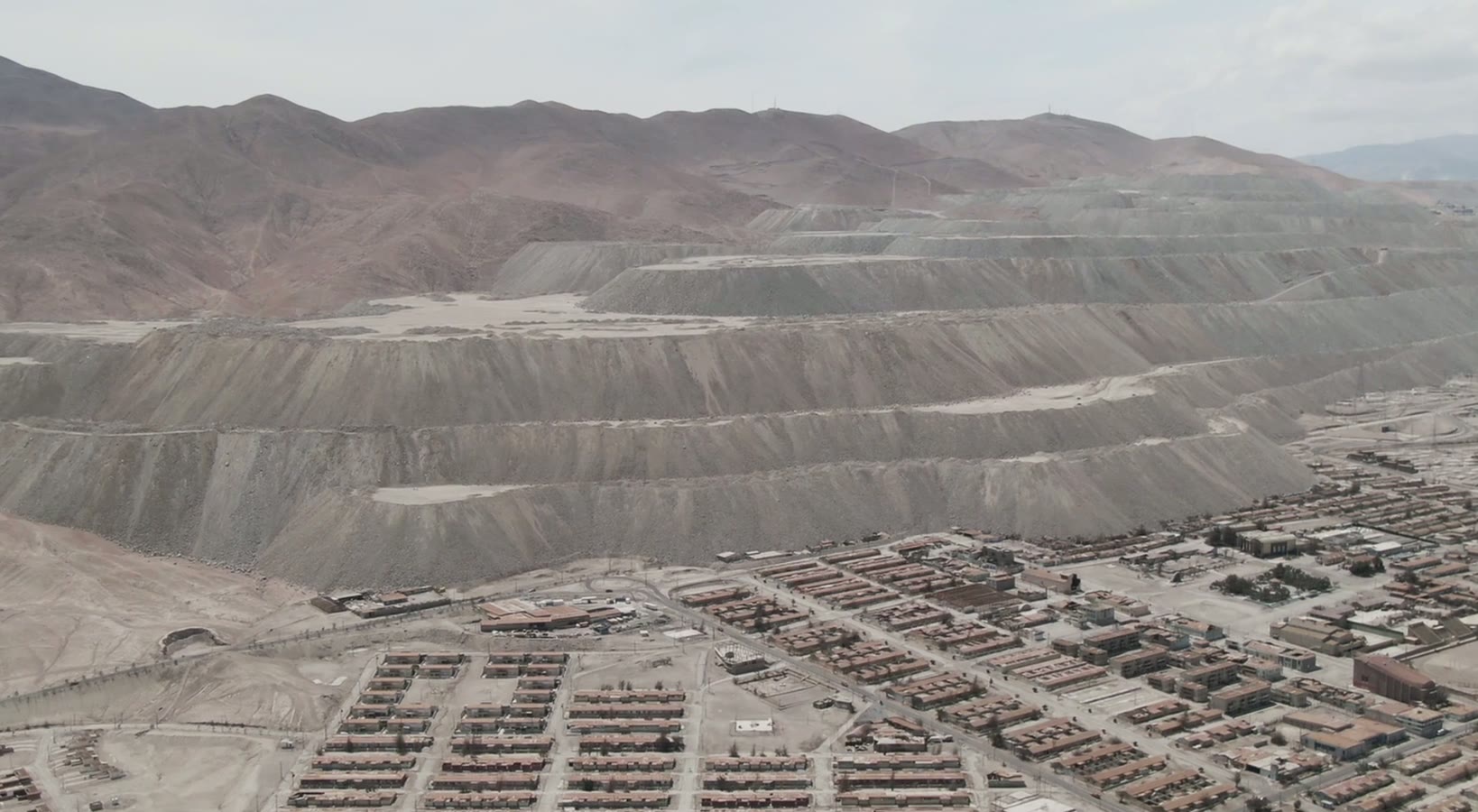 Aerial view of a mining district and terraced waste dumps against mountains