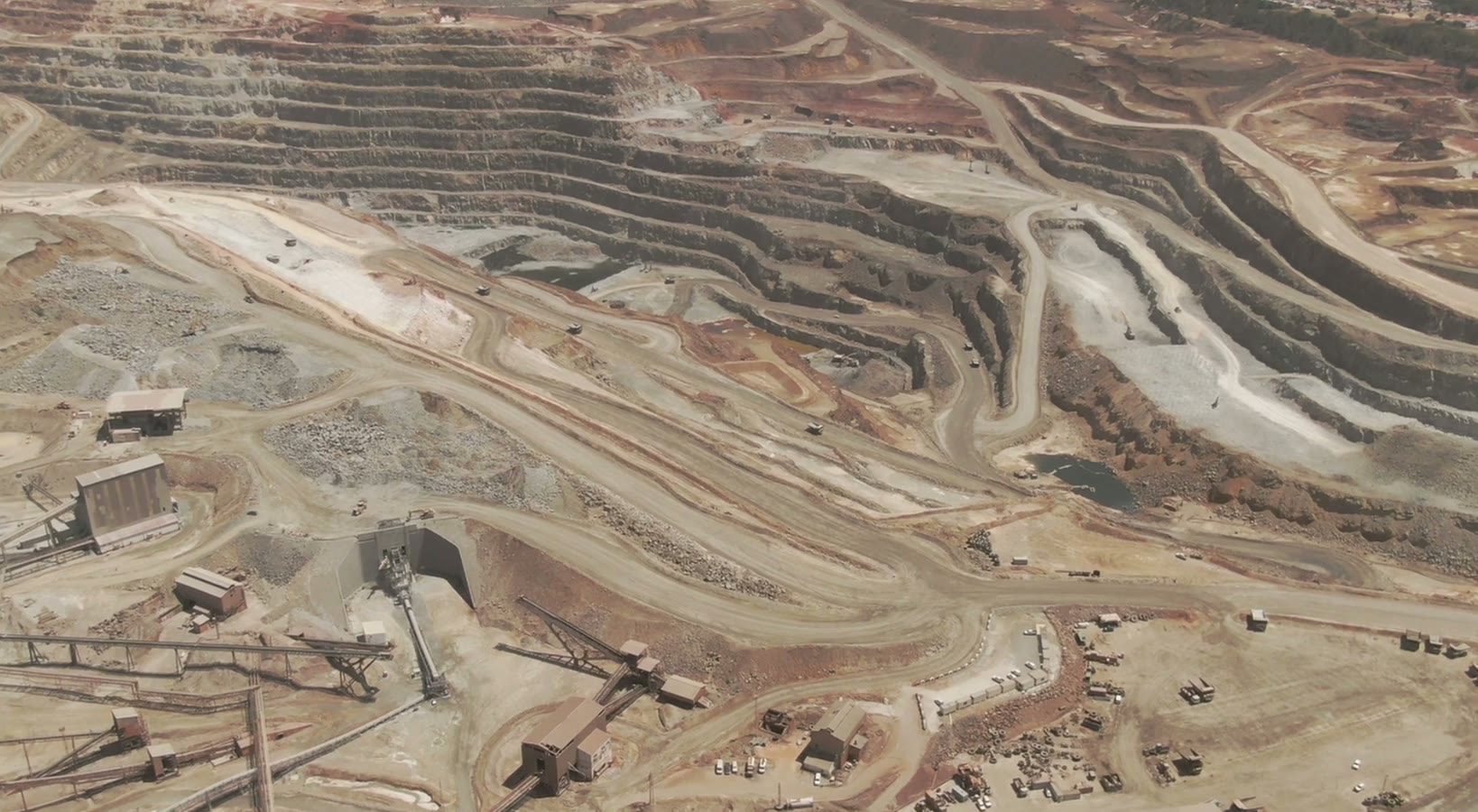 Aerial view of terraced open-pit mine benches with conveyors