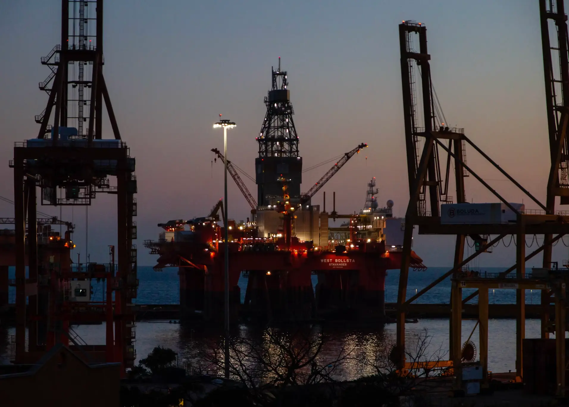 Offshore drilling rig moored at port at dusk